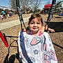 Ayla joined the competition — help win amazing prizes! toddler, child, swing, blanket, butterfly, playground, outdoor, sunny, happy, smile, park, people, trees, play_equipment, woodchips, clothing, person, daylight, recreation, fun