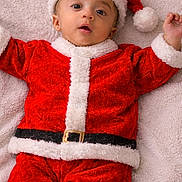 Ayaansh joined the competition — help win amazing prizes! baby, belly, blanket, child, christmas_outfit, cute, face, festive, happy, headwear, holiday, indoor, infant, lying_down, portrait, red_clothing, santa_hat, smiling, soft_texture, white_fur_trim