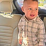 toddler, child, car_interior, car_seat, plaid_shirt, smiling, standing, sunlight, window, seat, headrest, clothing, person, young_child, cute, happy, indoor, vehicle, seatbelt, casual