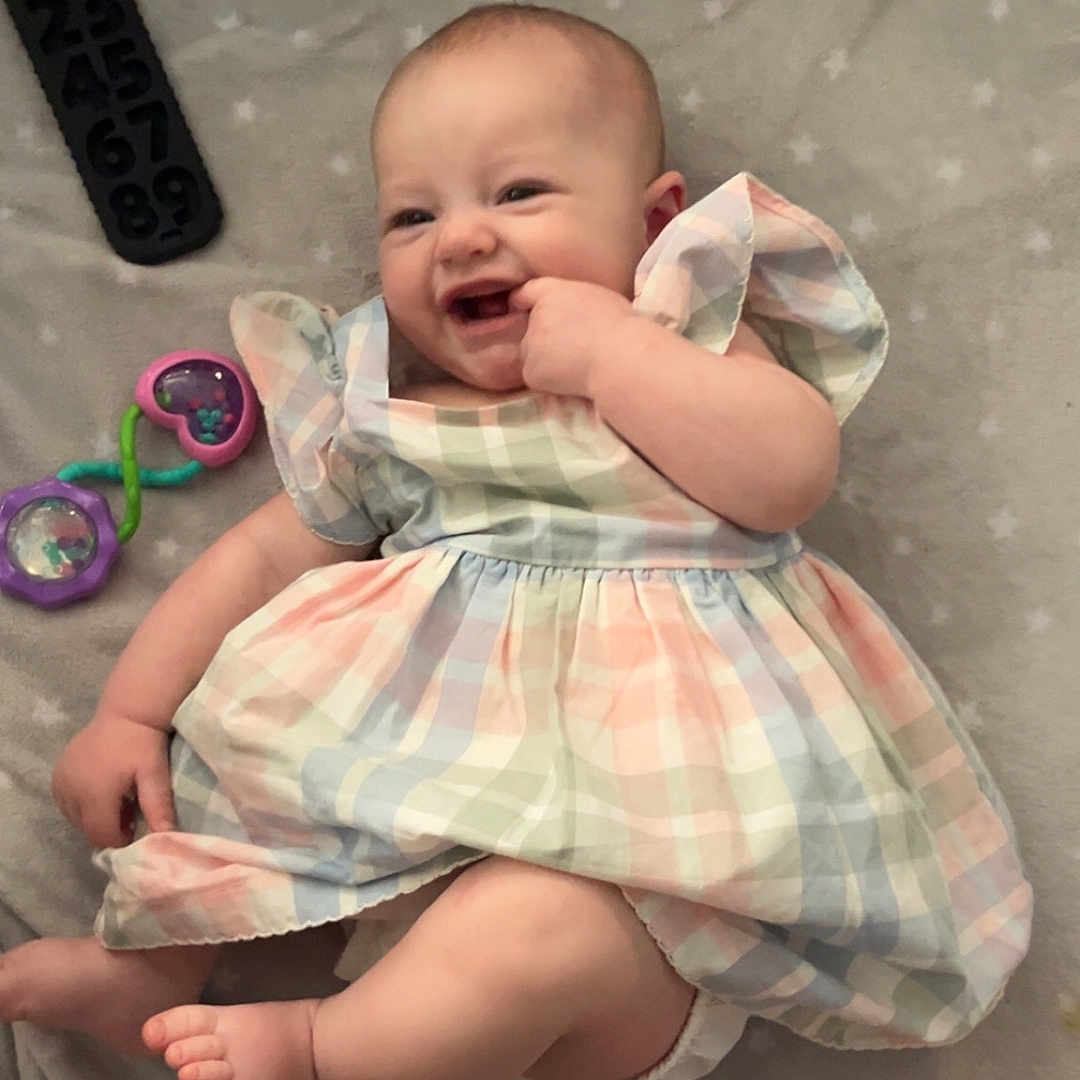 Ellarae is registered to the contest to win money with this photo: baby, babylaughing, bed, bodypart, clothing, couch, dress, face, finger, furniture, hand, happy, head, laughing, newborn, person, photography, portrait, sitting, smile