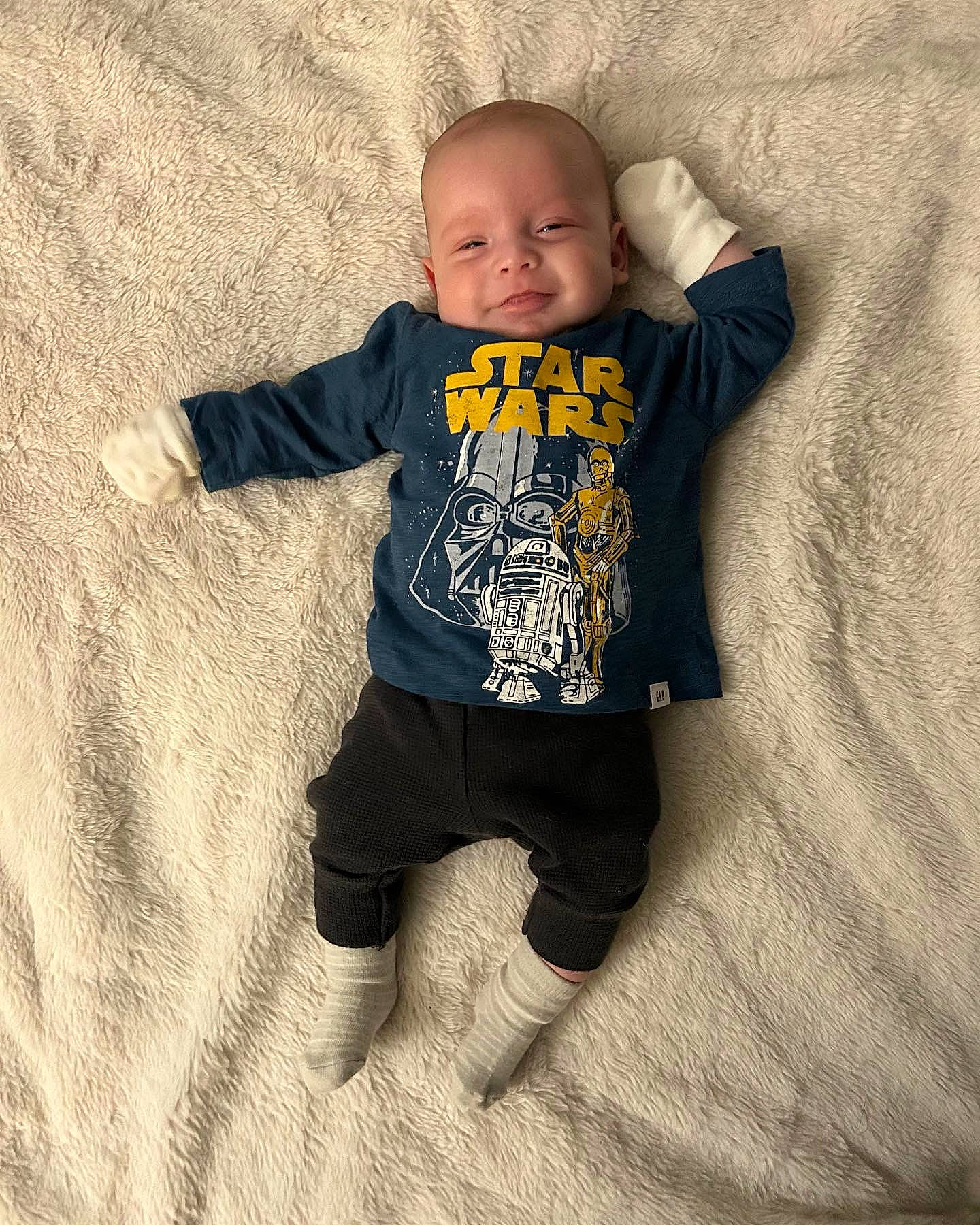 Eugene is registered to the contest to win money with this photo: arm, baby, baby_toddler_clothing, child, comfort, eye, face, flash_photography, flooring, grey, happy, head, linens, long_sleeved_t_shirt, person, sitting, skin, sleeve, t_shirt, toddler