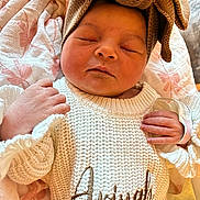 Ariyah joined the competition — help win amazing prizes! newborn, baby, infant, sleeping, knitted_sweater, headband, bow, blanket, closeup, cute, peaceful, soft_lighting, indoors, portrait, child, hand, face, skin, resting, cozy