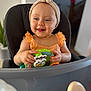 Nina participe au concours pour gagner de l'argent avec cette photo : baby, child, high_chair, headband, orange_clothing, toy, zebra_toy, smiling, happy, indoor, person, infant, cute, playful, hands, face, seat, furniture, skin, expression