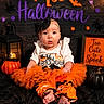 baby, child, halloween, orange, tutu, pumpkin, costume, black_bow, lantern, sign, decorations, cute, festive, portrait, sitting, holiday, celebration, black_background, infant, expression