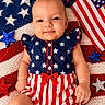 Maddie is registered to the contest to win money with this photo: american_flag, baby, child, clothing, dress, festive, fourth_of_july, glitter, holiday, infant, lying_down, outdoor_theme, patriotic, photography, portrait, red_white_blue, sitting, smiling, star_spangled, stars