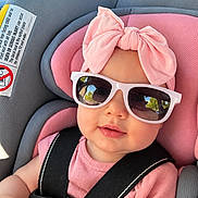 Maddie is registered to the contest to win money with this photo: baby, child, infant, car_seat, sunglasses, pink_bow, pink_clothing, harness, portrait, sitting, face, smiling, outdoor, automobile, safety_belt, fashion, headband, close_up, photography, cute
