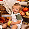 child, toddler, smiling, portrait, autumn, fall, pumpkin, gourd, leaves, outdoor, seasonal, cozy, blanket, wooden_crate, rustic, sitting, overalls, green_shirt, white_shoes, photography