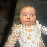 Angelina is registered to the contest to win money with this photo: baby, infant, child, face, eyes, clothing, pattern, pumpkin, flowers, long_sleeve, leather, couch, skin, expression, portrait, cute, indoors, laying, young, apparel