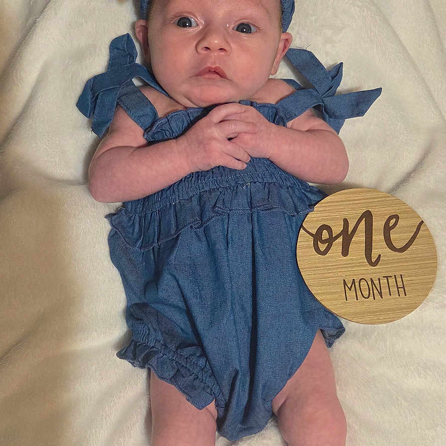 Lydia joined the competition — help win amazing prizes! baby, infant, child, portrait, lying_down, blue_outfit, bow, headband, blanket, milestone, one_month, wooden_sign, wide_eyed, hands_clasped, bare_feet, indoor, soft_lighting, centered_composition, newborn, photography