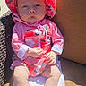 Lydia is registered to the contest to win money with this photo: baby, infant, child, portrait, outdoor, sunlight, hat, floral_hat, pink_clothing, strawberry_pattern, flower_pattern, sitting, chair, cushion, towel, patio, bare_feet, serious_expression, face, photograph