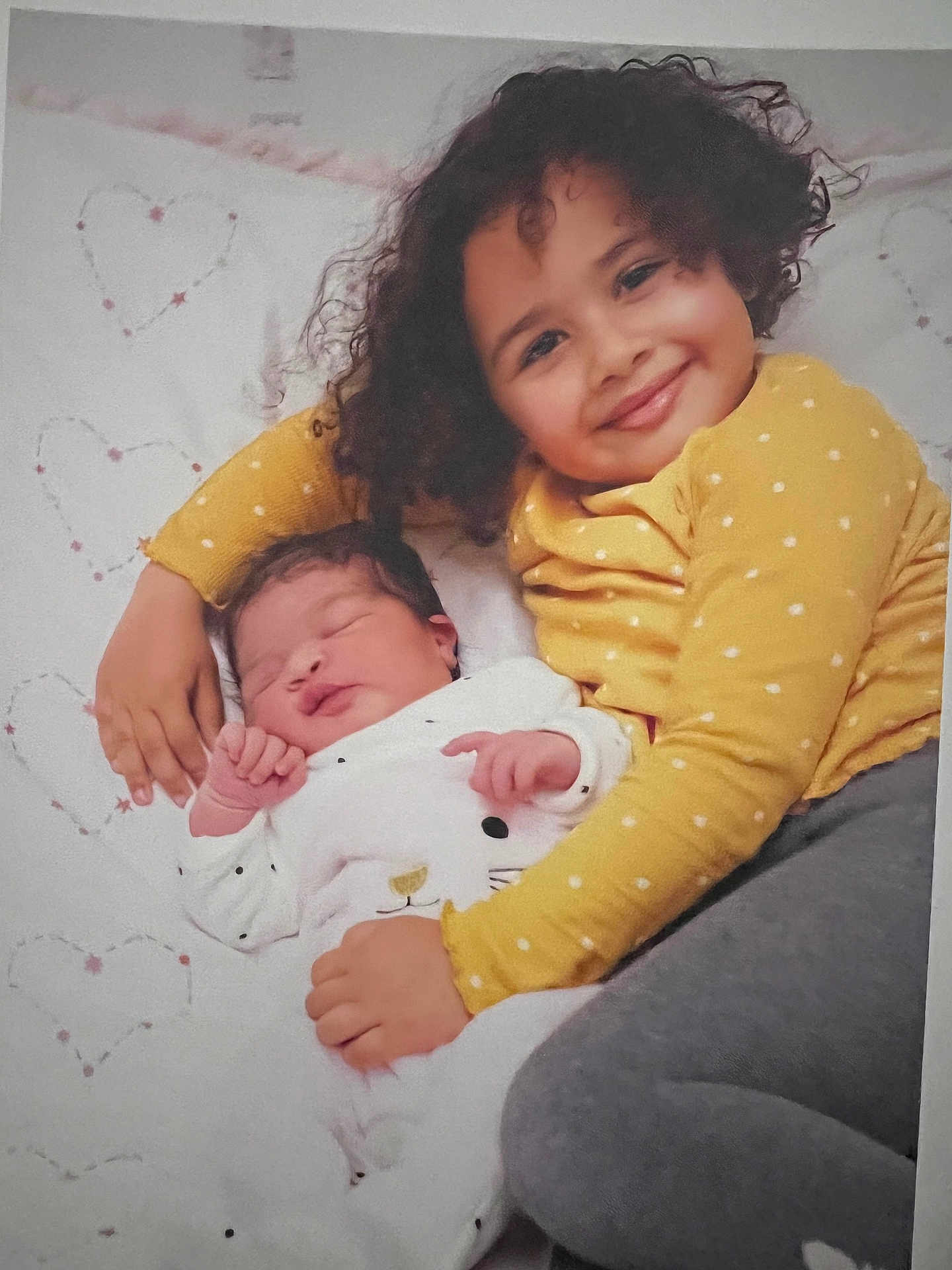 Lina participe au concours pour gagner de l'argent avec cette photo : toddler, newborn, baby, child, smiling, sleeping, cuddling, yellow_shirt, white_blanket, heart_pattern, curly_hair, polka_dot, cozy, family, indoors, soft_lighting, peaceful, portrait, cute, happy