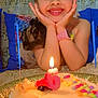 child, birthday_cake, candle, smile, happy, celebration, indoor, curtain, pillow, colorful, watch, cake, girl, party, table, decor, young, face, hands, cute