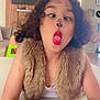 child, curly_hair, fur_vest, red_lips, face_paint, indoor, table, playful, tongue_out, crossed_eyes, smiling, person, furniture, home, funny_face, child_playing, casual_clothing, portrait, young, cute