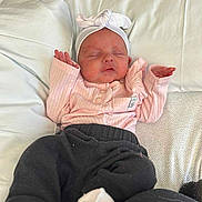 Presley is registered to the contest to win money with this photo: baby, bed, black_pants, child, cozy, cute, headband, indoors, infant, laying_down, newborn, peaceful, person, pillow, pink_clothing, portrait, resting, sleeping, soft_light, white_socks