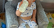Isaiah is registered to the contest to win money with this photo: baby, infant, child, bottle, feeding, sitting, playpen, plush_toy, elephant_toy, caterpillar_toy, colorful, play_mat, toys, indoor, portrait, face, eyes, short_hair, clothing, safe