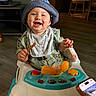 Isaiah joined the competition — help win amazing prizes! baby, child, infant, smiling, happy, portrait, hat, bib, onesie, seated, walker, activity_center, toy, breadstick, food, indoor, living_room, television, wood_floor, smartphone