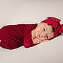 baby, infant, red_bow, red_wrap, headband, lying_down, soft_background, newborn, cute, peaceful, portrait, child, indoors, studio_shot, wrapped, sleepy, small_hands, small_feet, face, skin