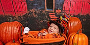 Ivy is registered to the contest to win money with this photo: baby, pumpkin, basket, hat, orange_clothing, smile, halloween, decor, black_cauldron, floor, wood, background_painting, window, door, fence, leaf, cozy, festive, child, portrait