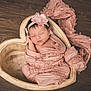 newborn, baby, sleeping, pink, headband, heart_shaped_bowl, wooden_floor, wrapped, soft_cloth, peaceful, infant, cute, portrait, indoors, resting, close_up, adorable, baby_girl, delicate, cozy