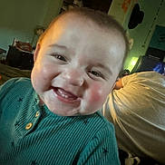 Stetson joined the competition — help win amazing prizes! baby, infant, smiling, teeth, rosy_cheeks, closeup, portrait, teal_sweater, ribbed_sweater, indoor, bedroom, blanket, adult_in_background, face, eyes, cheeks, mouth, happy, candid, toddler