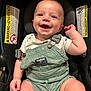 Henry joined the competition — help win amazing prizes! baby, smiling, car_seat, overalls, green_clothing, infant, child, happy, cute, straps, warning_label, seat, indoors, person, face, skin, head, short_hair, casual_clothing, expression