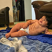 Rudy joined the competition — help win amazing prizes! baby, blanket, diaper, floor, furniture, indoor, living_room, person, plush, couch, child, skin, hair, relaxing, chubby, cute, home, resting, young, portrait