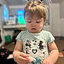 Kinzel is registered to the contest to win money with this photo: toddler, child, indoor, curly_hair, pigtails, polka_dot, shirt, cartoon_print, spray_bottle, focused, cute, young_child, person, face, skin, hair, casual_clothing, carpet, blurred_background, home
