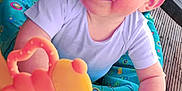 Maylon a rejoint le concours — aidez-le/la à gagner de superbes lots ! baby, child, toy, cap, play_table, colorful, blue_eyes, smiling, outdoor, wooden_deck, baby_seat, pink_toy, plastic_toy, hand, clothing, face, person, happy, closeup, playing