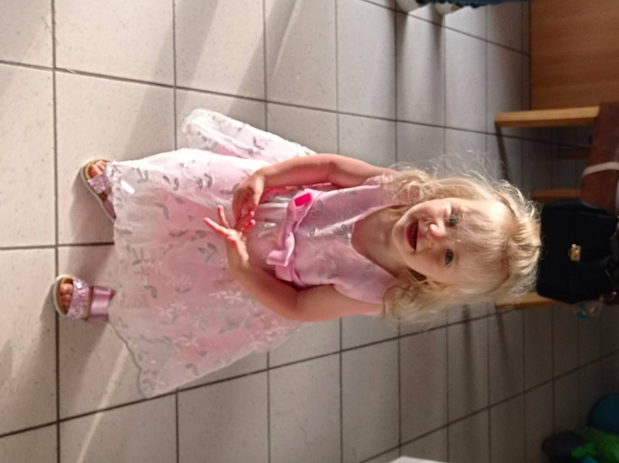 Kyra participe au concours pour gagner de l'argent avec cette photo : baby, baby_products, baby_toddler_clothing, child, dress, flesh, flooring, fun, human_leg, knee, linens, magenta, pattern, person, pink, room, smile, toddler