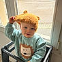 Hugo a rejoint le concours — aidez-le/la à gagner de superbes lots ! toddler, child, knitted_hat, bear_ears, sweater, lion_graphic, high_chair, indoor, window, curious, cute, light, baby, clothing, smiling, portrait, person, young_child, face, hand