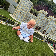 Tobias-John joined the competition — help win amazing prizes! baby, child, grass, miniature_castle, lego, outdoor, greenery, toy_figures, blue_outfit, white_socks, cute, smiling, playful, detailed, castle, park, daylight, nature, curious, sitting