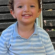 Haron participe au concours pour gagner de l'argent avec cette photo : child, toddler, smiling, curly_hair, striped_shirt, polo_shirt, shorts, outdoor, stairs, daylight, happy, sitting, face, skin, person, casual_clothing, young_child, cute, portrait, playful