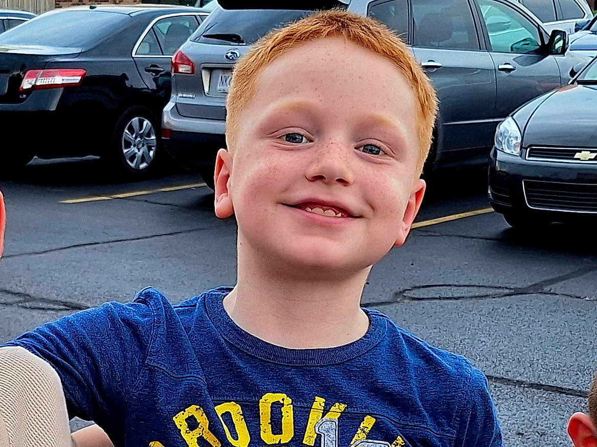 Truman joined the competition — help win amazing prizes! child, boy, red_hair, freckles, smile, blue_shirt, parking_lot, cars, outdoor, casual_clothing, happy, face, person, portrait, daylight, people, vehicle, asphalt, road, street