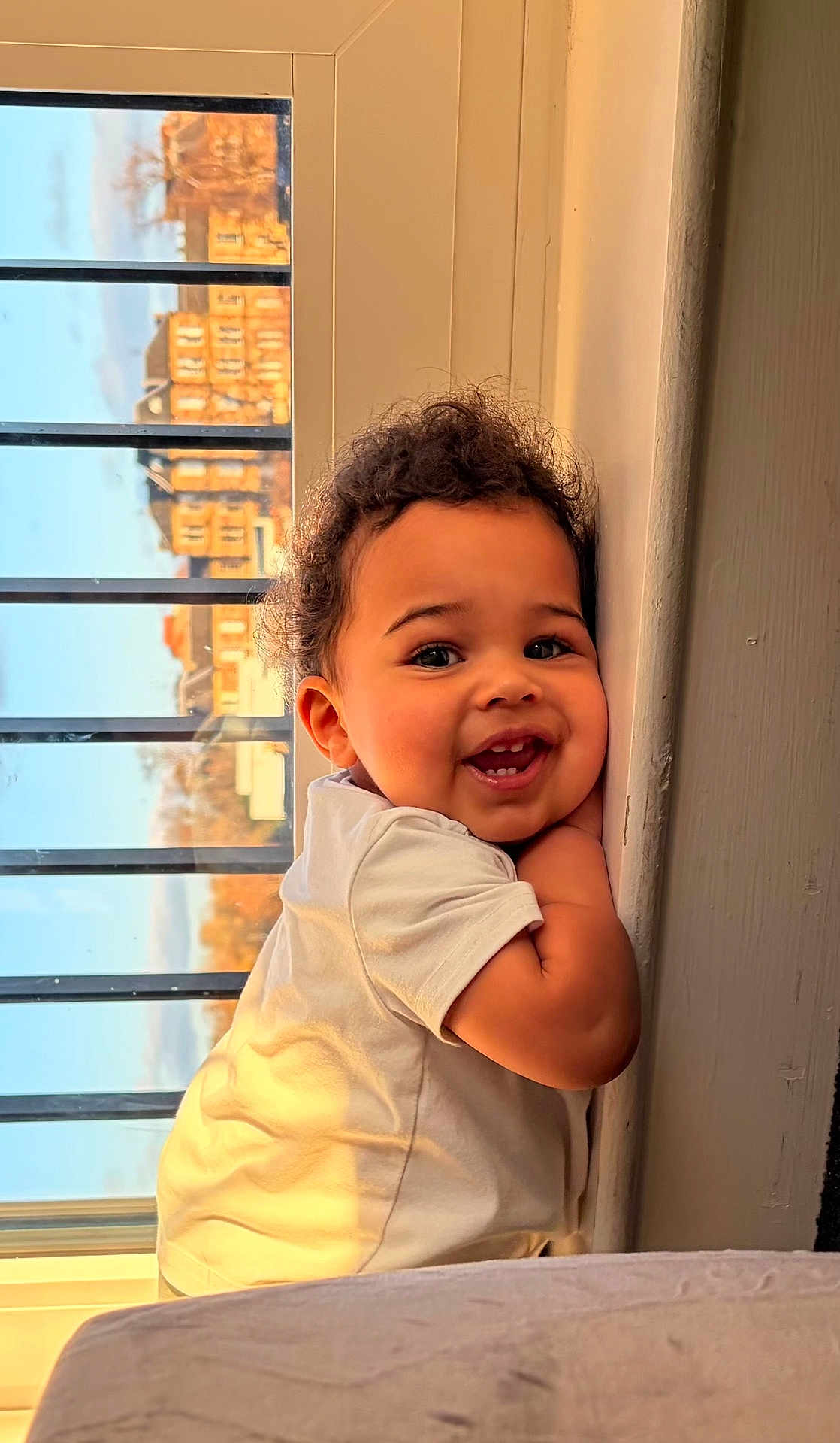 Grayson joined the competition — help win amazing prizes! toddler, child, smiling, curly_hair, white_shirt, window, sunlight, indoor, face, happy, cute, portrait, baby, cheerful, young_child, skin, expression, person, daylight, home