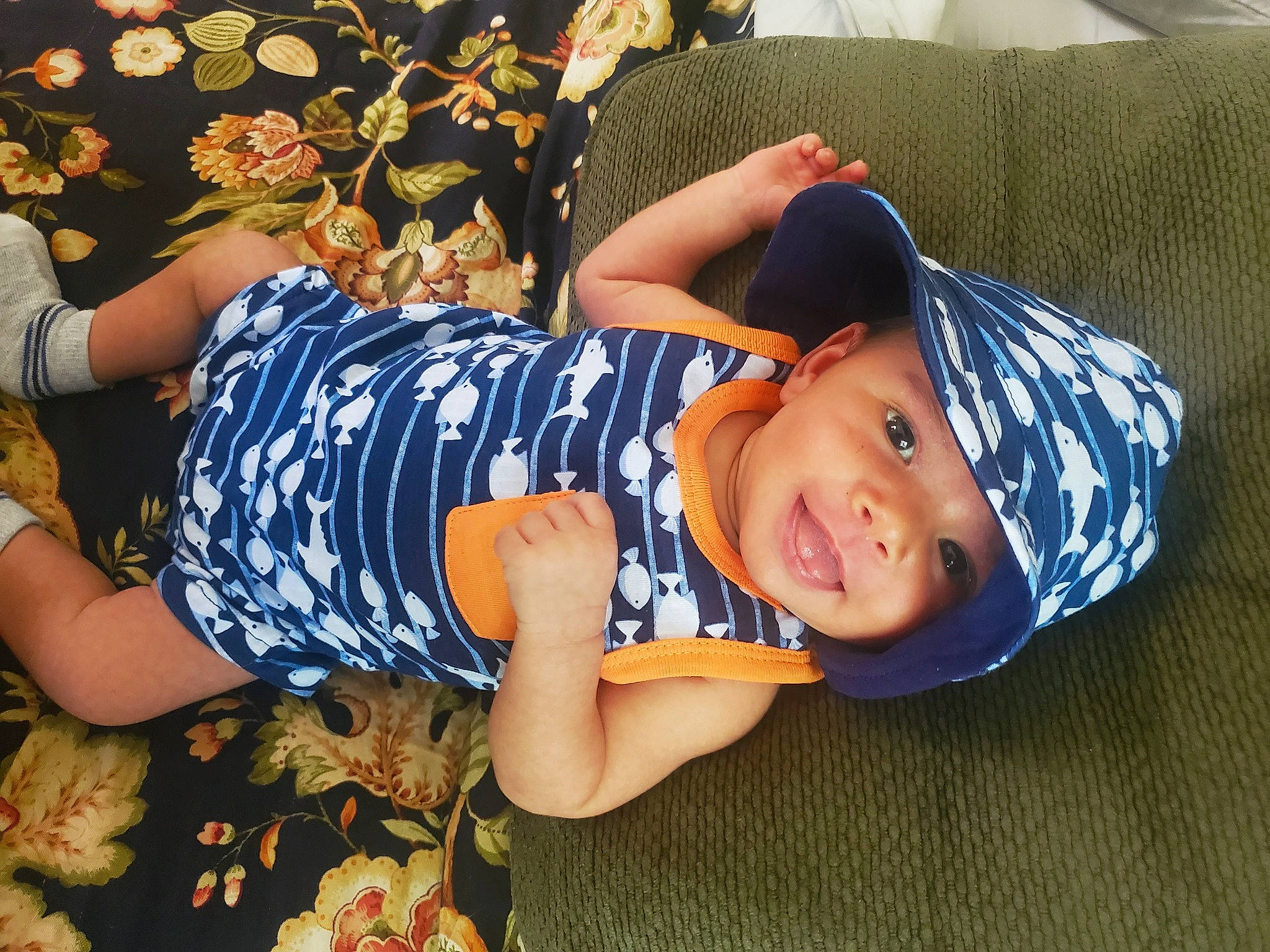 Beaux is registered to the contest to win money with this photo: baby_toddler_clothing, child, comfort, cool, electric_blue, fashion_accessory, fun, grass, happy, hat, headgear, headwear, human_leg, leisure, pattern, person, sitting, sleeve, smile, t_shirt