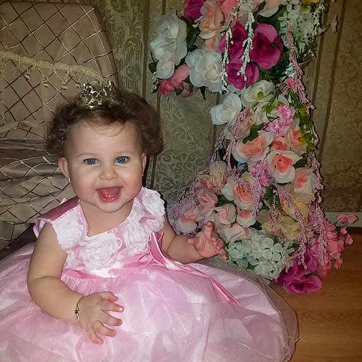 Salina joined the competition — help win amazing prizes! baby, bracelet, celebration, chair, child, crown, curly_hair, cute, dress, floor, flower_arrangement, happy, headwear, indoor, party, pink_dress, portrait, sitting, smiling, toddler
