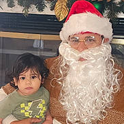 Milan joined the competition — help win amazing prizes! child, toddler, santa, beard, glasses, santa_hat, garland, ornaments, christmas_decor, fireplace, cozy_sweater, holding, indoor, portrait, family, festive, holiday, cute, sitting, young_child