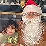 child, toddler, santa, beard, glasses, santa_hat, garland, ornaments, christmas_decor, fireplace, cozy_sweater, holding, indoor, portrait, family, festive, holiday, cute, sitting, young_child