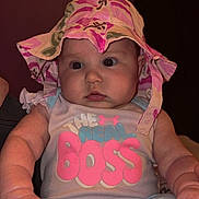 Rynlee is registered to the contest to win money with this photo: baby, infant, child, hat, bucket_hat, onesie, text_on_clothing, chubby_cheeks, big_eyes, hands, sitting, portrait, indoor, pink, blue_clothing, adorable, cute, person, closeup, soft_lighting