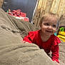 toddler, child, crawling, red_shirt, blanket, indoor, curtains, toys, smiling, happy, face, person, home, soft_texture, furniture, playful, young_child, cozy, light, casual