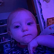 Nova is registered to the contest to win money with this photo: child, toddler, face, hand, indoor, purple_light, sweater, blanket, furniture, decorations, shelf, toy, curious, thoughtful, portrait, person, home, casual, expression, young