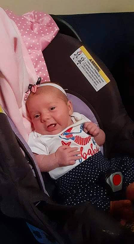 Delaney is registered to the contest to win money with this photo: baby, baby_carriage, baby_products, baby_toddler_clothing, car_seat, carmine, cheek, child, comfort, couch, event, finger, fun, happy, lap, nail, person, pink, sitting, skin