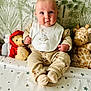 acorn_pattern, baby, bib, blue_eyes, child, cozy, cute, giraffe_toy, indoor, infant, pajamas, person, plush_toys, portrait, room, sitting, soft_toys, stars_pattern, teddy_bear, wallpaper