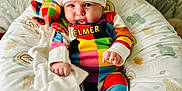Cobe joined the competition — help win amazing prizes! baby, baby_garment, blanket, child, colorful, colorful_clothing, cozy, cushion, cute, elmer, hat, indoor, infant, patterned_background, playful, plush_toy, portrait, seated, smiling_face, soft_toy