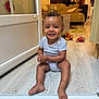 toddler, child, smiling, indoor, floor, door, toy, living_room, couch, stairs, wood_floor, casual_clothing, happy, person, home, curly_hair, baby, clap, play, furniture