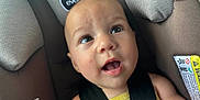 Emma joined the competition — help win amazing prizes! baby, child, car_seat, seatbelt, straps, face, expression, curious, indoors, person, head, skin, clothing, yellow, cute, infant, closeup, safety, car, seat