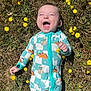 baby, infant, smiling, grass, yellow_flowers, dinosaur_onesie, outdoor, nature, sunlight, happy, child, lying_down, greenery, cute, joyful, one_person, grass_field, playful, spring, barefoot
