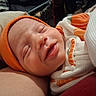 newborn, baby, infant, sleeping, face, portrait, orange_cap, swaddled, blanket, cozy, indoor, closeup, peaceful, pout, closed_eyes, soft_lighting, textile, bundled, caregiver, snuggling