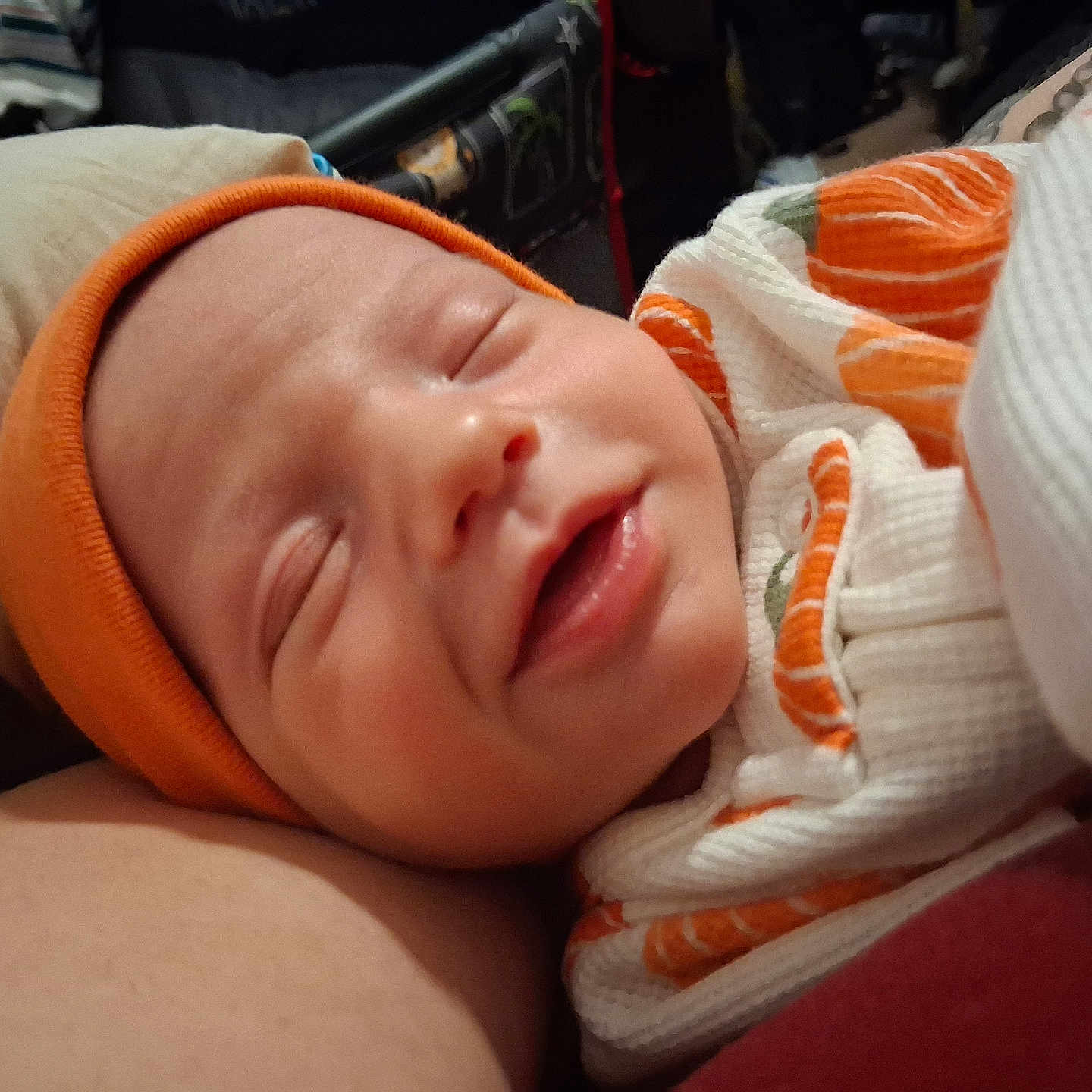 Raymond is registered to the contest to win money with this photo: newborn, baby, infant, sleeping, face, portrait, orange_cap, swaddled, blanket, cozy, indoor, closeup, peaceful, pout, closed_eyes, soft_lighting, textile, bundled, caregiver, snuggling