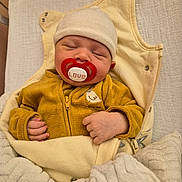 Mathéo a rejoint le concours — aidez-le/la à gagner de superbes lots ! baby, pacifier, sleeping, blanket, hat, yellow_clothing, cozy, infant, cute, resting, bed, soft, newborn, wrapped, indoor, child, small_hands, zipped_jacket, comfort, nap